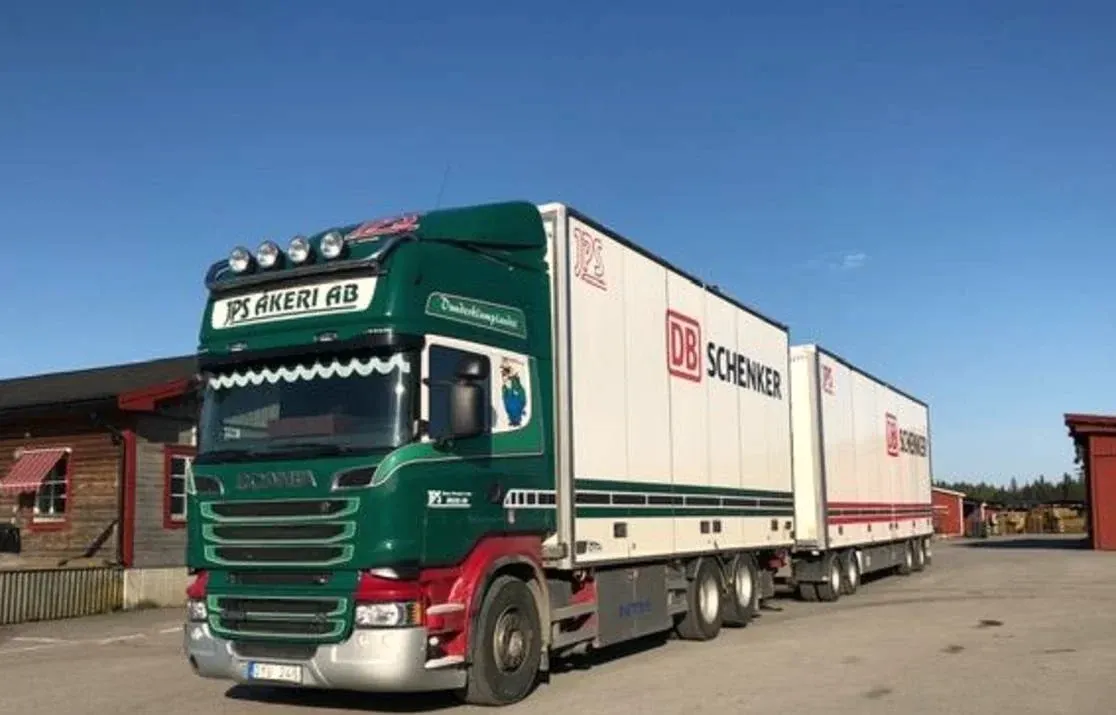 Grön och röd Scania med två skåp uppställd på terminalplanen.